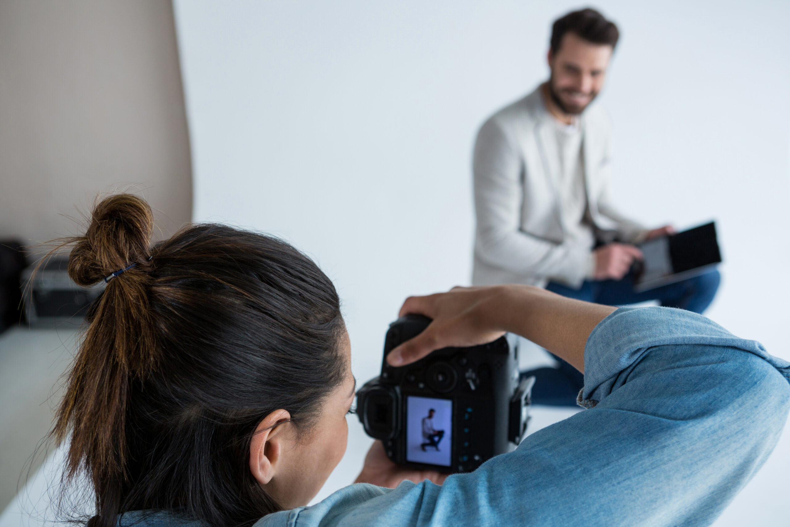 Eine Frau fotografiert einen Mann mit Laptop in der Hand