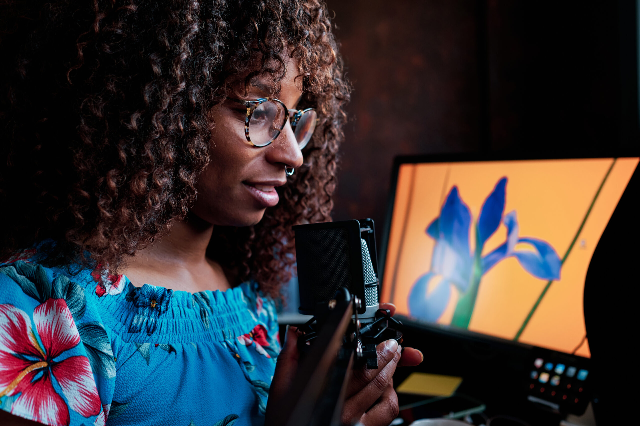 Eine Frau spricht in ein Mikrofon vor einem Bildschirm